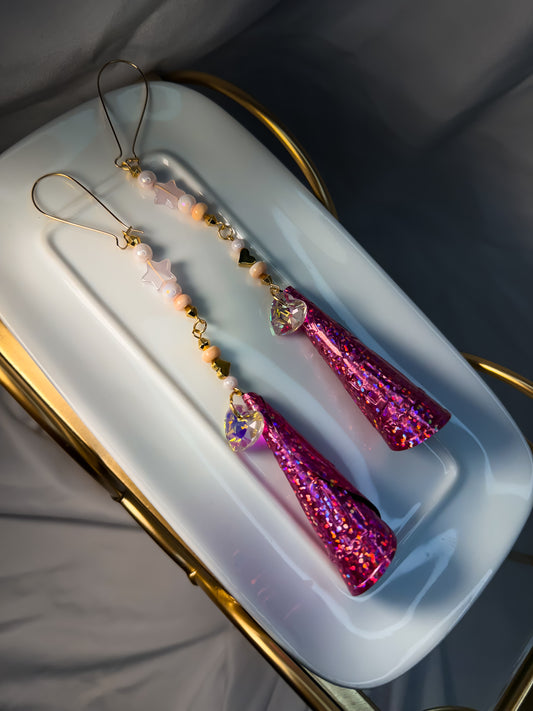 Shimmering pink glitter jingle earrings embellished with pink conch, gold beads, pink glass stars beads, and crystal hearts